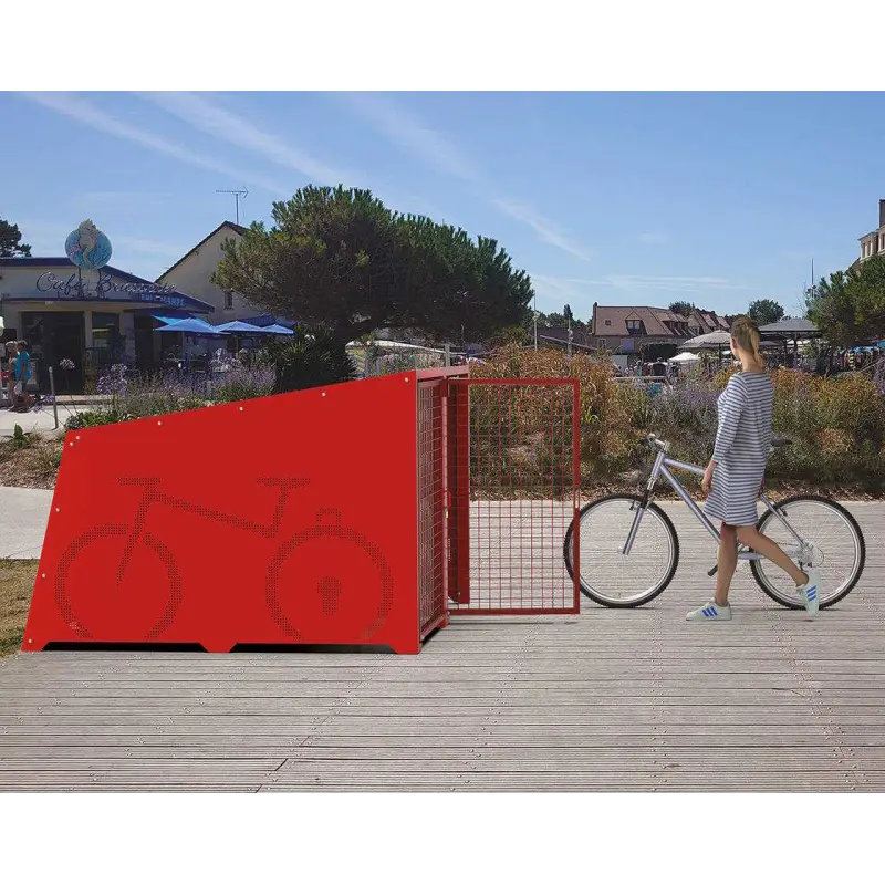 Rote Fahrradbox Berlin mit geöffneter Gittertür und Radfahrerin auf einer gepflasterten Promenade im öffentlichen Raum.